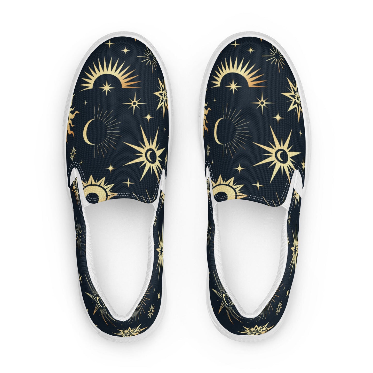 Top-down view of a pair of slip-on canvas shoes featuring a dark navy background with a celestial pattern of gold suns, stars, and crescent moons. The shoes have white interiors and white rubber soles, displayed on a clean white background.