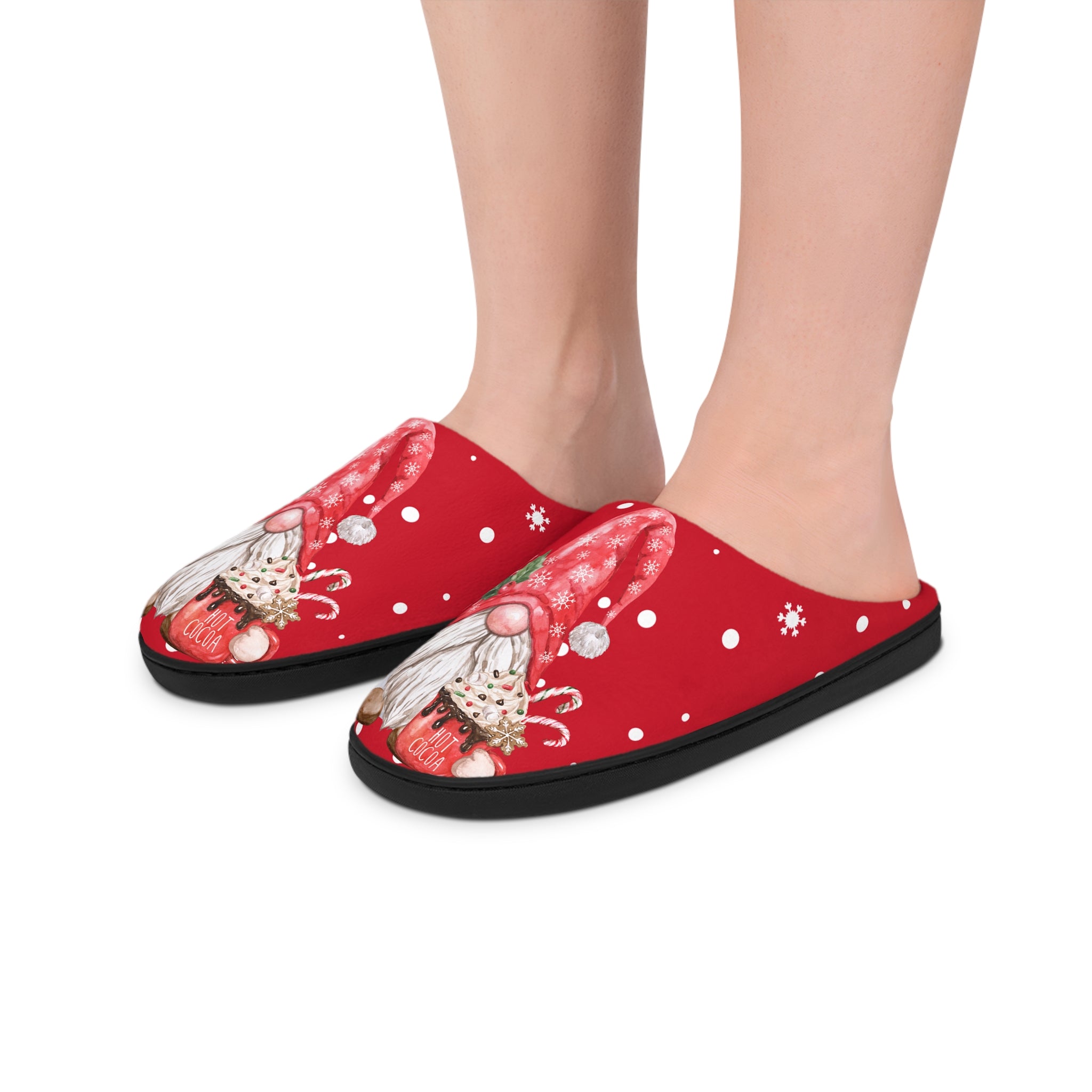 Red slippers with a Santa gnome design worn by a person on a white background