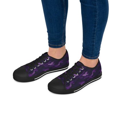 Purple camouflage sneakers worn with blue jeans on a white background