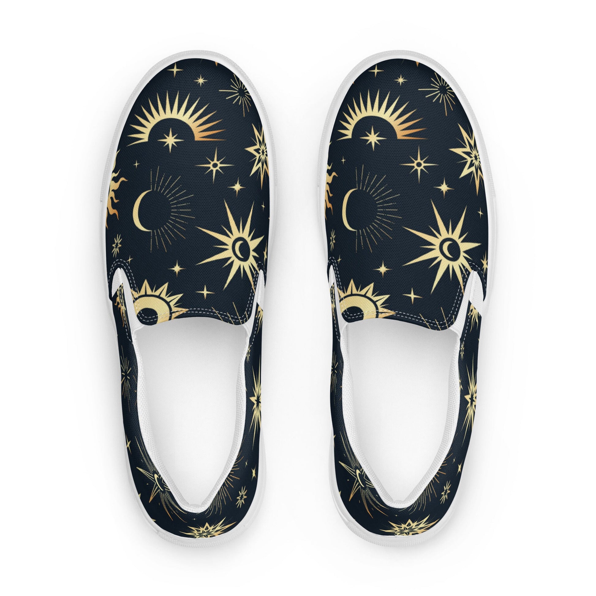 Top-down view of a pair of slip-on canvas shoes featuring a dark navy background with a celestial pattern of gold suns, stars, and crescent moons. The shoes have white interiors and white rubber soles, displayed on a clean white background.
