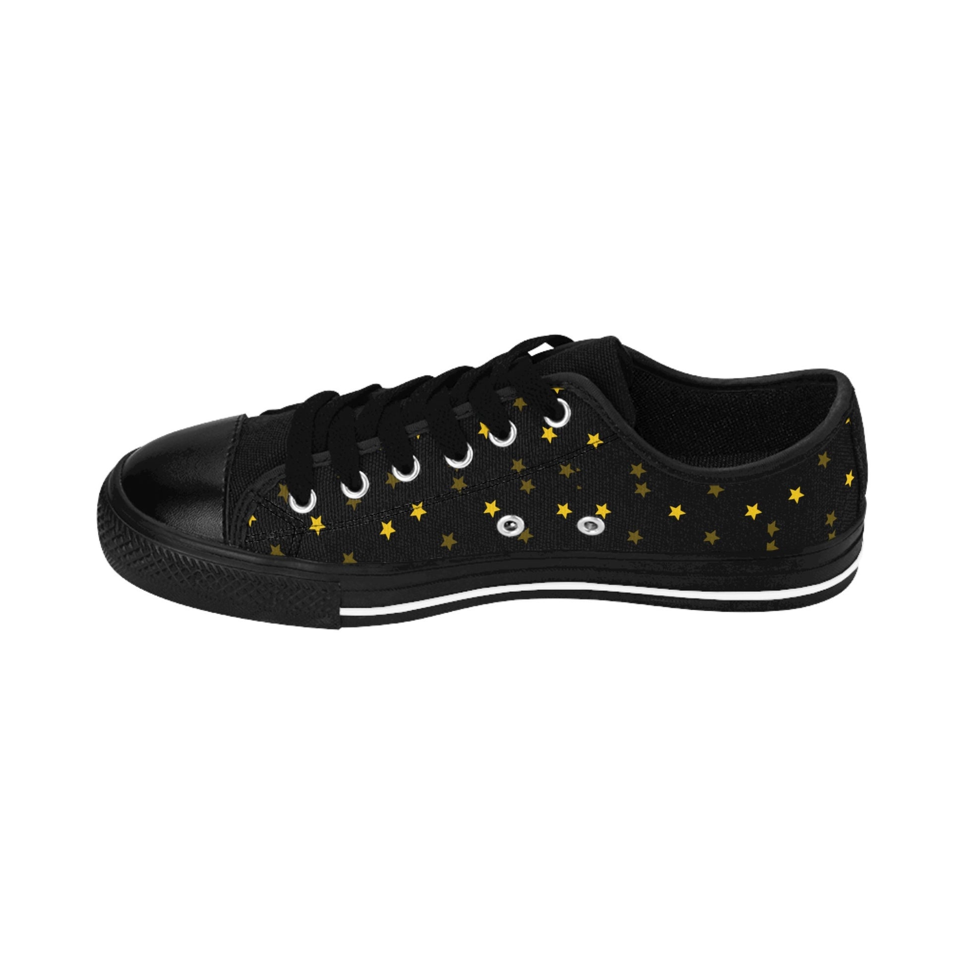 A single black low-top sneaker is displayed in a side view against a white background. The shoe features black laces, a black rubber toe cap, and a black sole with a white stripe. The canvas upper is decorated with a scattered pattern of small golden-yellow stars, creating a celestial, starry-night aesthetic.