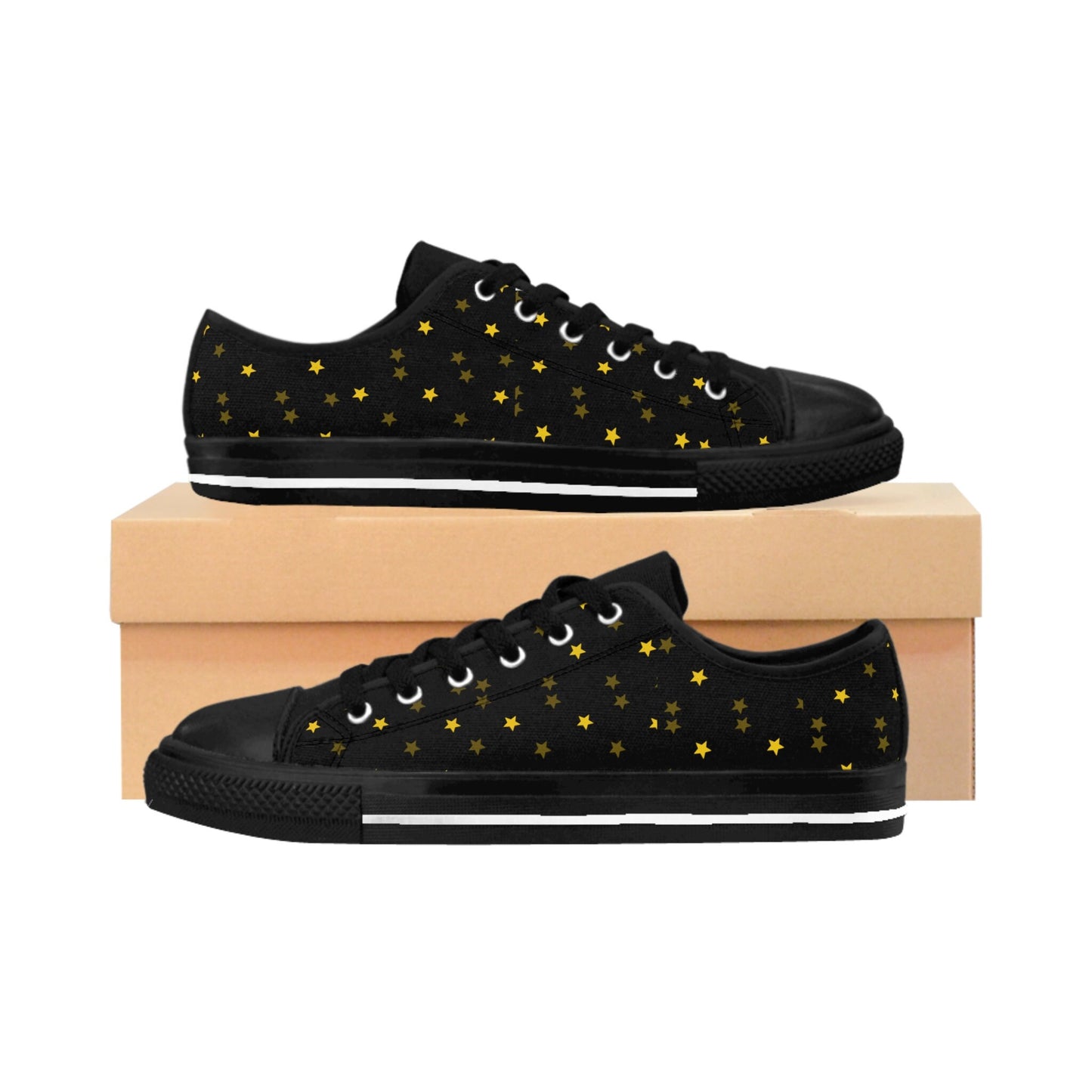 A pair of black low-top sneakers with black soles and laces is displayed against a white background. The shoes feature a scattered pattern of small gold stars across the sides. One shoe is placed on top of a light brown shoe box, while the other rests in front of it, showing the starry design from a side view.