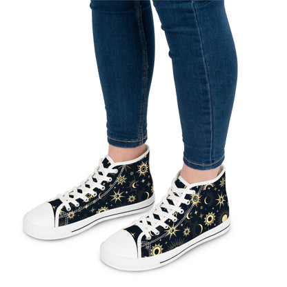 Close-up view of a person wearing high-top sneakers with a dark navy background and a celestial print featuring golden suns, moons, and stars. The shoes have white laces, white rubber toe caps, and white soles with a black stripe. The person is dressed in fitted blue jeans, with the focus on their lower legs and the detailed design of the shoes.