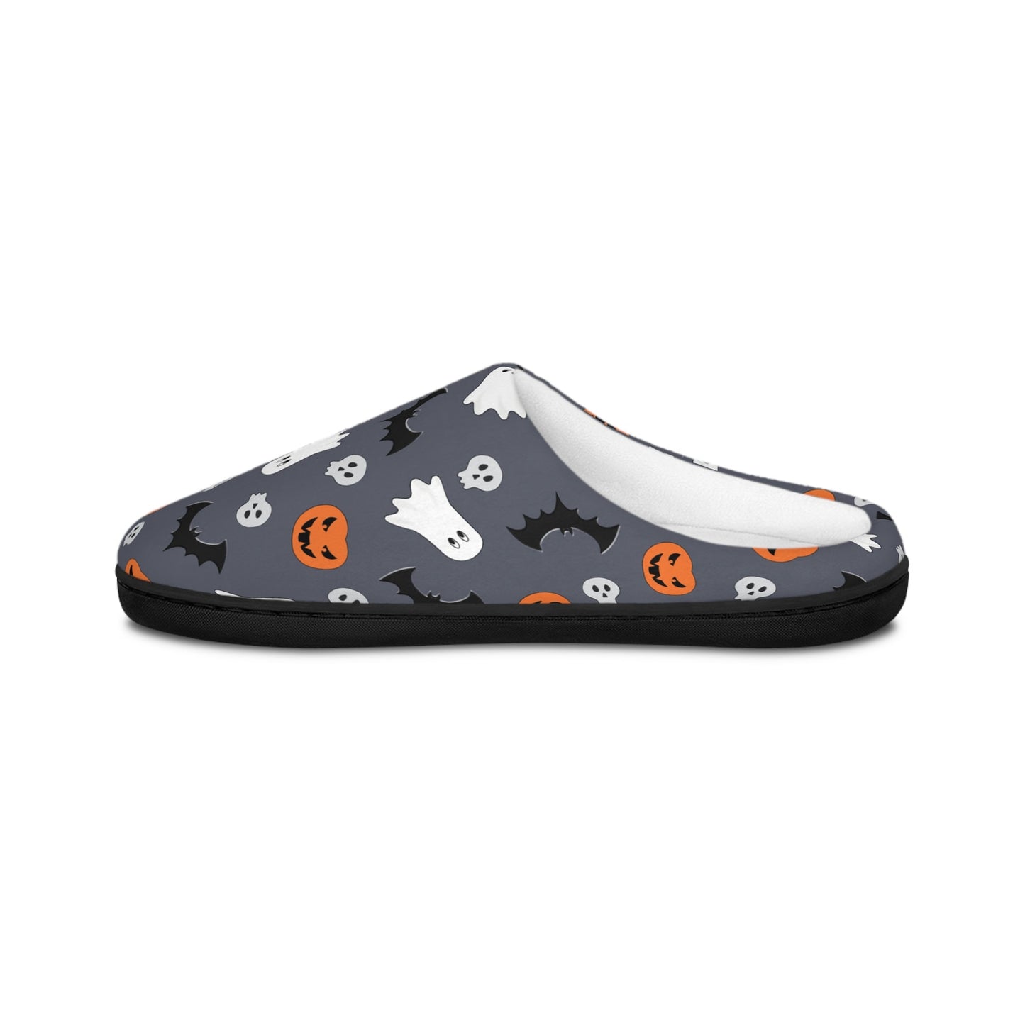 Side view of a cozy Halloween-themed slipper featuring a dark gray background with a festive pattern of white ghosts, black bats, orange jack-o&#39;-lanterns, and small skulls. The slipper has a soft white inner lining and a black sole, displayed against a plain white background.
