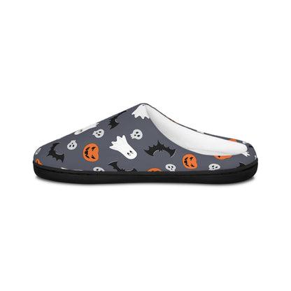 Side view of a cozy Halloween-themed slipper featuring a dark gray background with a festive pattern of white ghosts, black bats, orange jack-o&#39;-lanterns, and small skulls. The slipper has a soft white inner lining and a black sole, displayed against a plain white background.