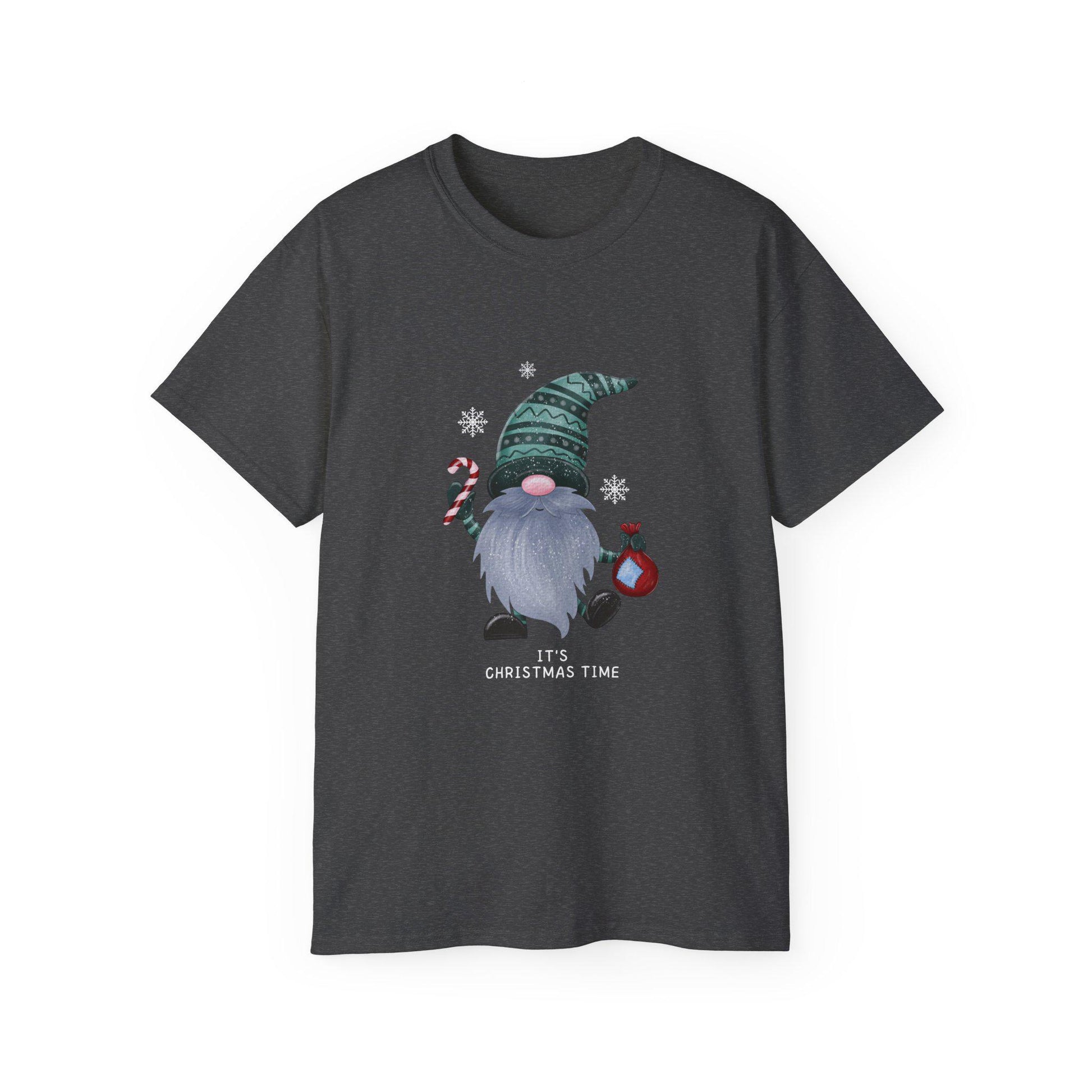 A dark heather gray unisex T-shirt is displayed against a white background, featuring a playful Christmas gnome graphic. The gnome has a long gray beard, a pink nose, and is wearing a green patterned hat. He holds a red and white candy cane in one hand and a red ornament in the other, surrounded by white snowflakes. Below the design, the phrase &quot;It&#39;s Christmas Time&quot; is printed in white. The shirt has a classic crew neck and short sleeves.