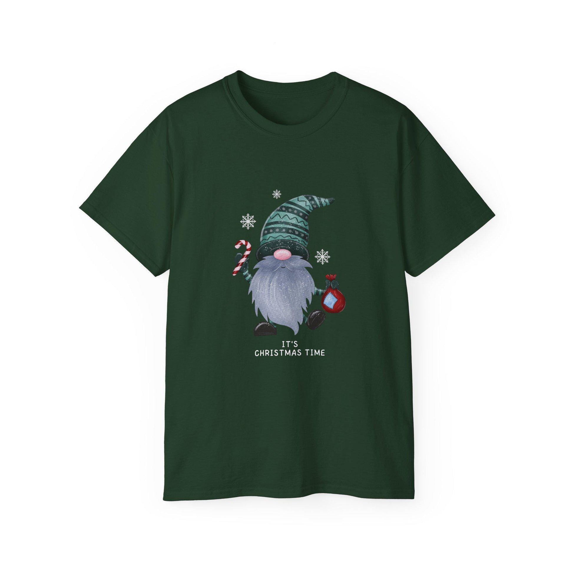A dark green unisex T-shirt is displayed against a white background, featuring a festive Christmas gnome graphic. The gnome has a long gray beard, a pink nose, and is wearing a patterned green hat. He holds a candy cane in one hand and a red ornament in the other, surrounded by white snowflakes. Below the illustration, the phrase &quot;It&#39;s Christmas Time&quot; is printed in white text. The shirt has a classic crew neck and short sleeves.