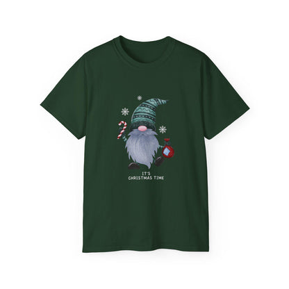 A dark green unisex T-shirt is displayed against a white background, featuring a festive Christmas gnome graphic. The gnome has a long gray beard, a pink nose, and is wearing a patterned green hat. He holds a candy cane in one hand and a red ornament in the other, surrounded by white snowflakes. Below the illustration, the phrase &quot;It&#39;s Christmas Time&quot; is printed in white text. The shirt has a classic crew neck and short sleeves.