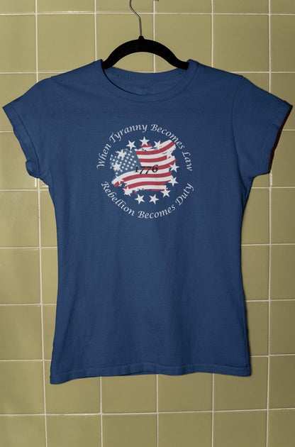 Blue fitted t-shirt hanging on a black hanger against a green tiled wall, featuring a patriotic design with a distressed American flag in the shape of the United States, surrounded by white stars and the quote &#39;When Tyranny Becomes Law, Rebellion Becomes Duty - 1776.