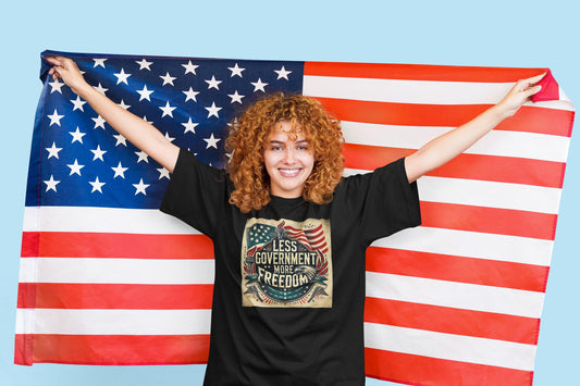 Cheerful woman holding American flag and wearing patriotic &#39;Less Government More Freedom&#39; t-shirt against light blue background, symbolizing liberty and independence.