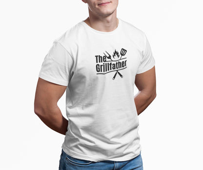 Man wearing a white T-shirt with the phrase “The Grillfather” and grilling icons, standing casually with hands behind his back against a plain background.