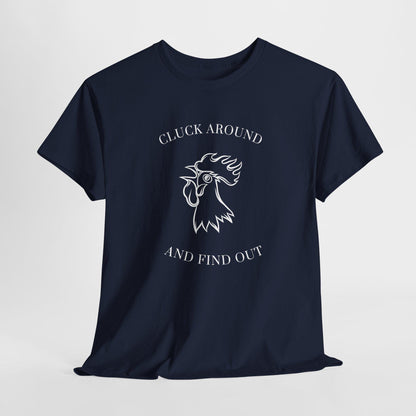 A navy blue t-shirt is laid flat against a white background. The shirt features a white graphic of a rooster&#39;s head with the words &quot;CLUCK AROUND&quot; above and &quot;AND FIND OUT&quot; below the illustration. It has a classic crew neckline and short sleeves, displayed in a casual, slightly wrinkled arrangement.