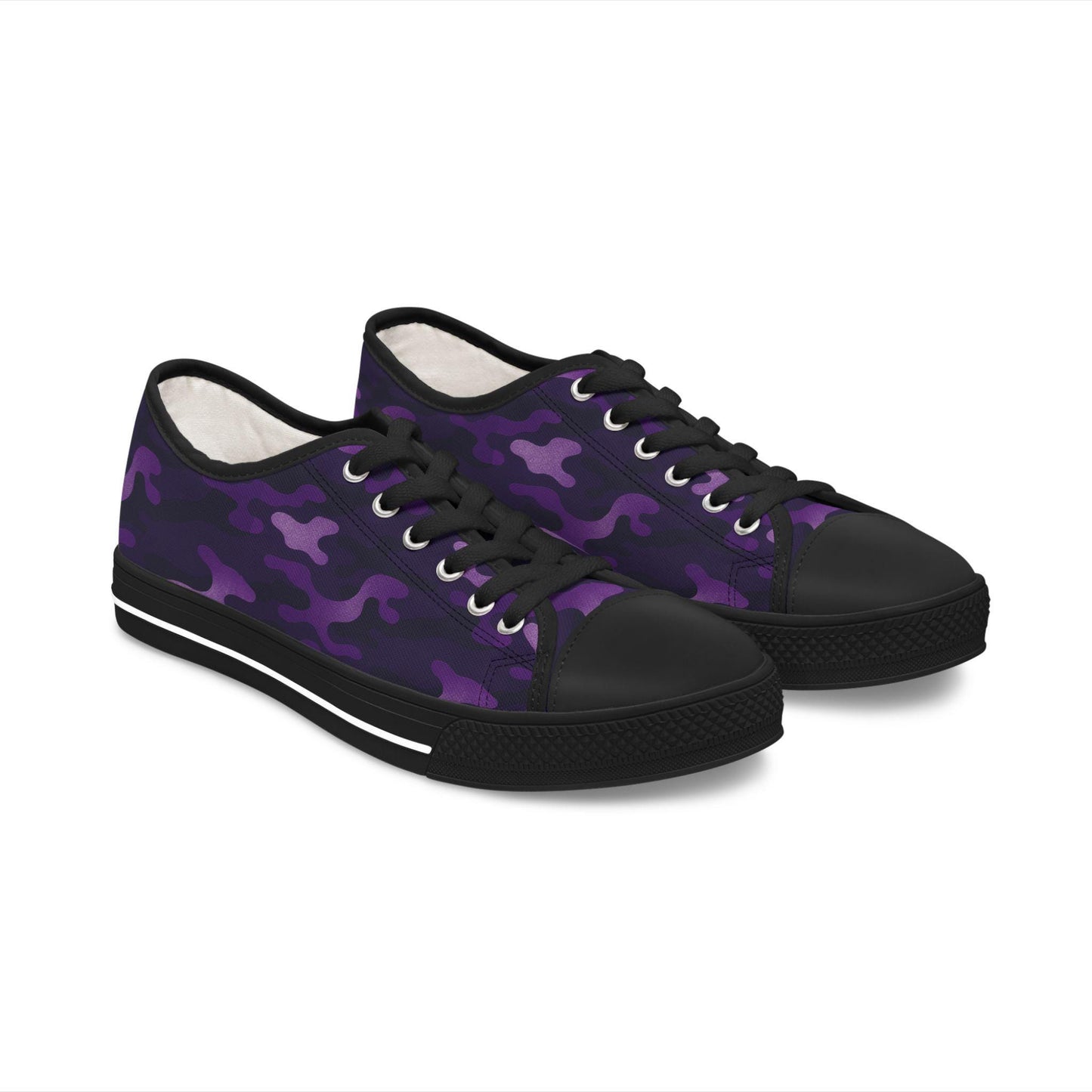 A pair of low-top canvas sneakers featuring a vibrant purple camouflage pattern with black and violet accents. The shoes are styled with black rubber soles, black toe caps, and black laces, giving them a bold, edgy look.