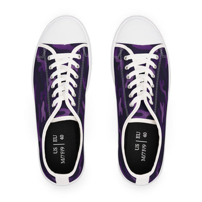 Top view of a pair of low-top canvas sneakers with a purple camouflage pattern, white rubber toe caps, and white laces. The insoles are black and printed with size details showing US M7/F9 and EU 40.