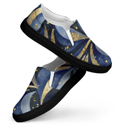 A pair of slip-on sneakers with a celestial-themed design featuring swirling patterns in deep blue, black, and gold tones. The shoes have black soles and a low-profile silhouette, with a white interior lining. The starry design resembles a cosmic night sky with gold flecks that mimic stars or glitter. The sneakers are positioned in a dynamic, overlapping display against a plain white background.