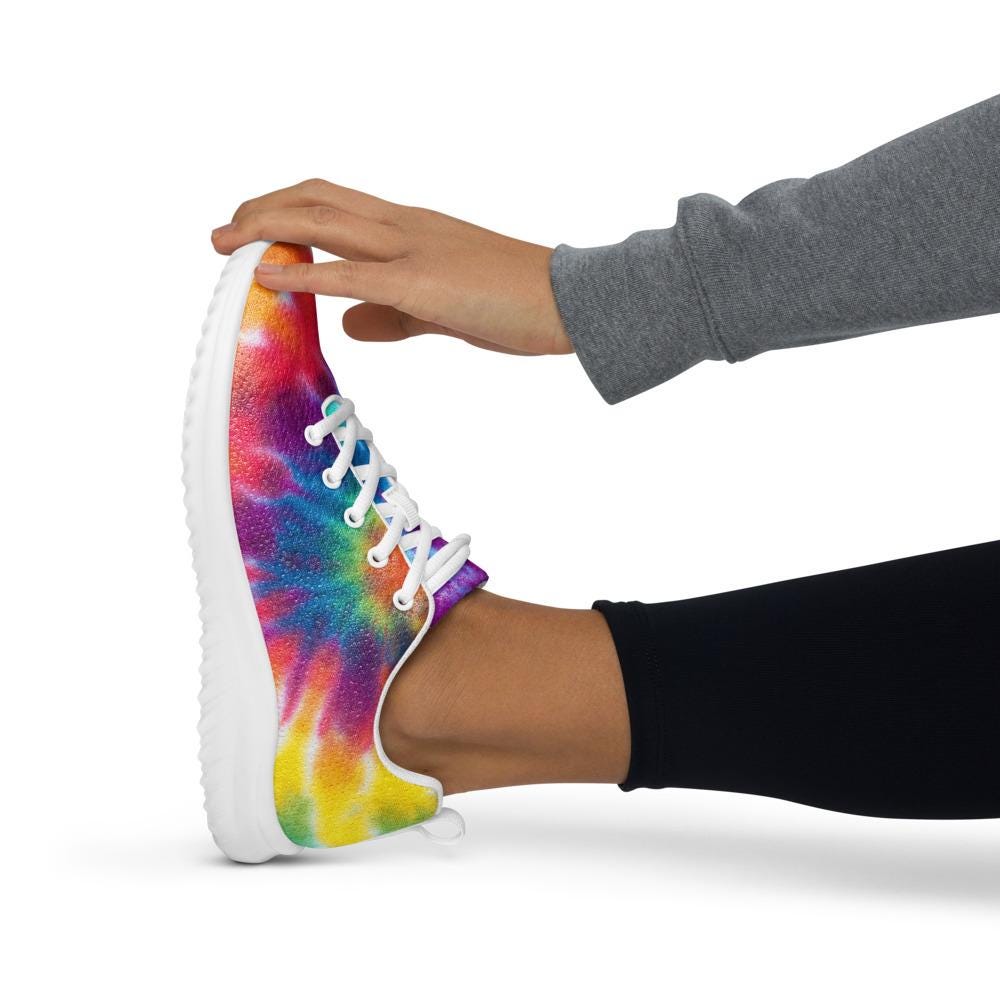 Person stretching in vibrant rainbow tie-dye athletic sneakers with white soles and laces—flexible, comfortable shoes ideal for workouts, running, and active lifestyles.