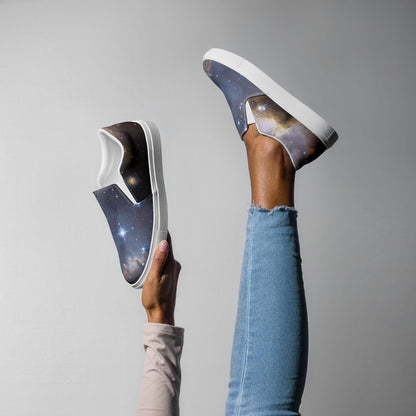 ChatGPT said:
Playful image of a person wearing light blue jeans, holding one leg in the air while showcasing a pair of galaxy-themed slip-on sneakers. One shoe is worn, and the other is held up by hand, both featuring a cosmic design with stars and nebulae, white elastic panels, and white soles. The background is plain light gray.