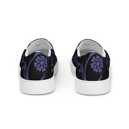 Back view of slip-on sneakers featuring a black canvas base with a decorative dark purple floral and vine design. The heels showcase a large stylized flower motif, and the shoes have white midsoles for a clean, modern contrast.