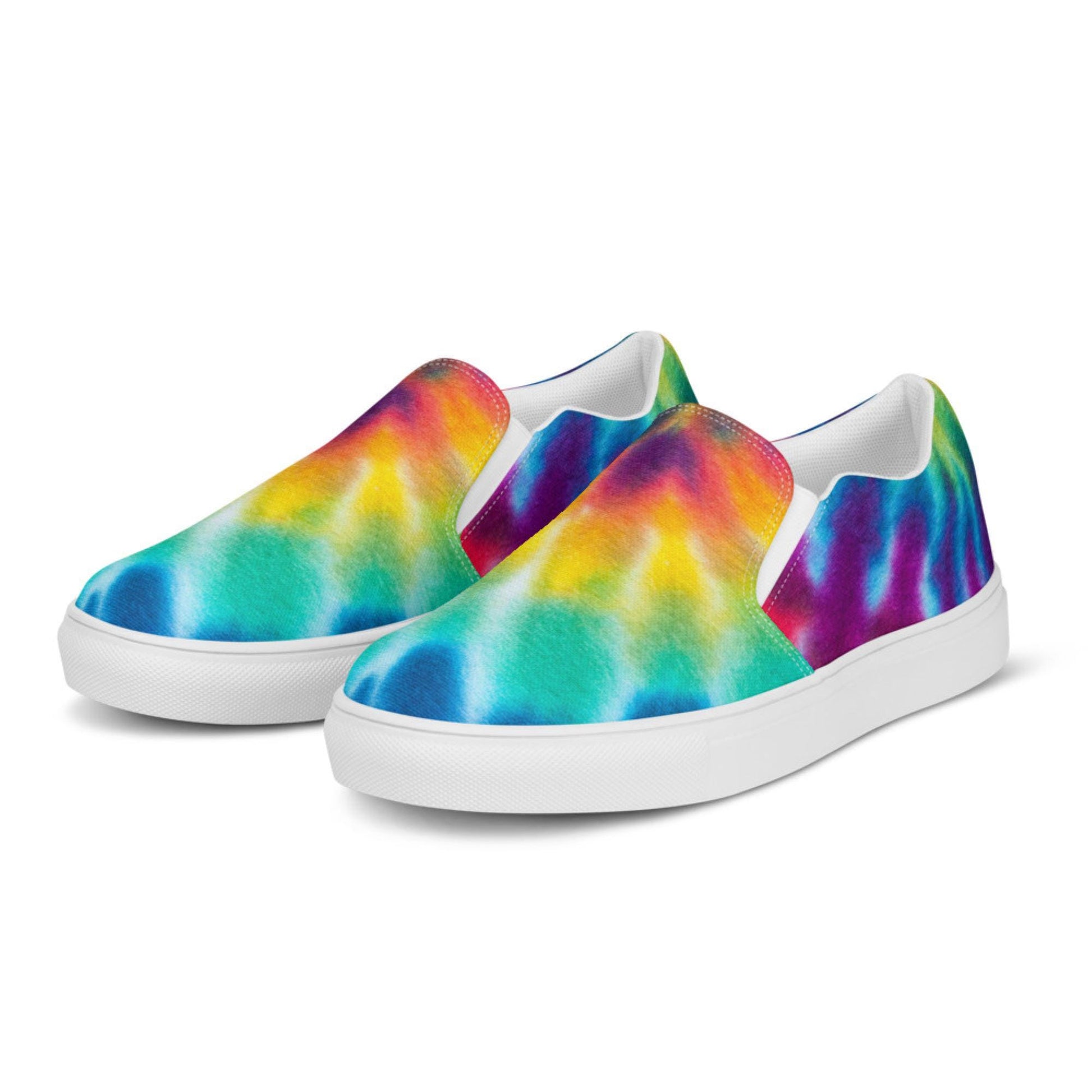 Front angled view of rainbow tie-dye slip-on canvas sneakers for women on a white background. These colorful casual shoes feature a bold blend of turquoise, aqua blue, yellow, orange, red, and purple in a smooth watercolor pattern. Built with a crisp white rubber sole and elastic side panels for easy wear and all-day comfort.