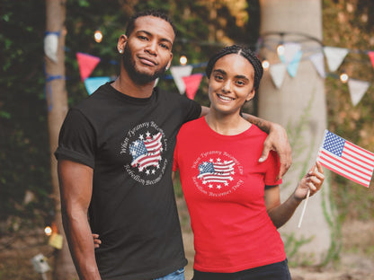 Patriotic couple at an outdoor celebration wearing matching &quot;When Tyranny Becomes Law, Rebellion Becomes Duty&quot; t-shirts with distressed American flag designs—man in black shirt, woman in red shirt holding a small U.S. flag.