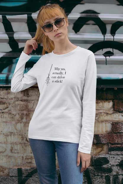 Woman wearing a white long-sleeve Halloween shirt featuring a black broomstick illustration and the humorous witch quote &quot;Why yes, actually, I can drive a stick!&quot; — perfect for spooky season style, witch-themed outfits, and fall festivities. Fun Halloween shirt for women, ideal for October parties, autumn layering, and casual witchcore fashion.