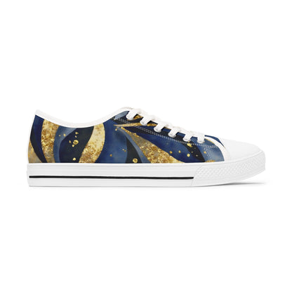 A side view of a stylish low-top canvas sneaker with a celestial-themed design in deep blue, gold, and black tones. The shoe features swirling patterns that resemble stars and cosmic waves, accented with gold speckles. It has a white rubber sole, white toe cap, white laces, and a thin black stripe along the midsole. The background is plain white, emphasizing the shoe&#39;s artistic and eye-catching design.