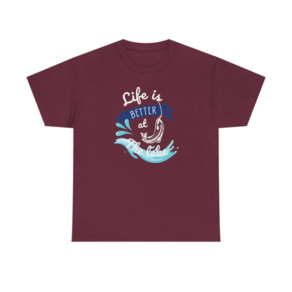 Flat lay of a maroon unisex t-shirt featuring a vibrant graphic design with the phrase &#39;Life is Better at the Lake.&#39; The design includes a fish hook, blue water splashes, and a navy banner, printed in white, blue, and aqua colors on a plain background.
