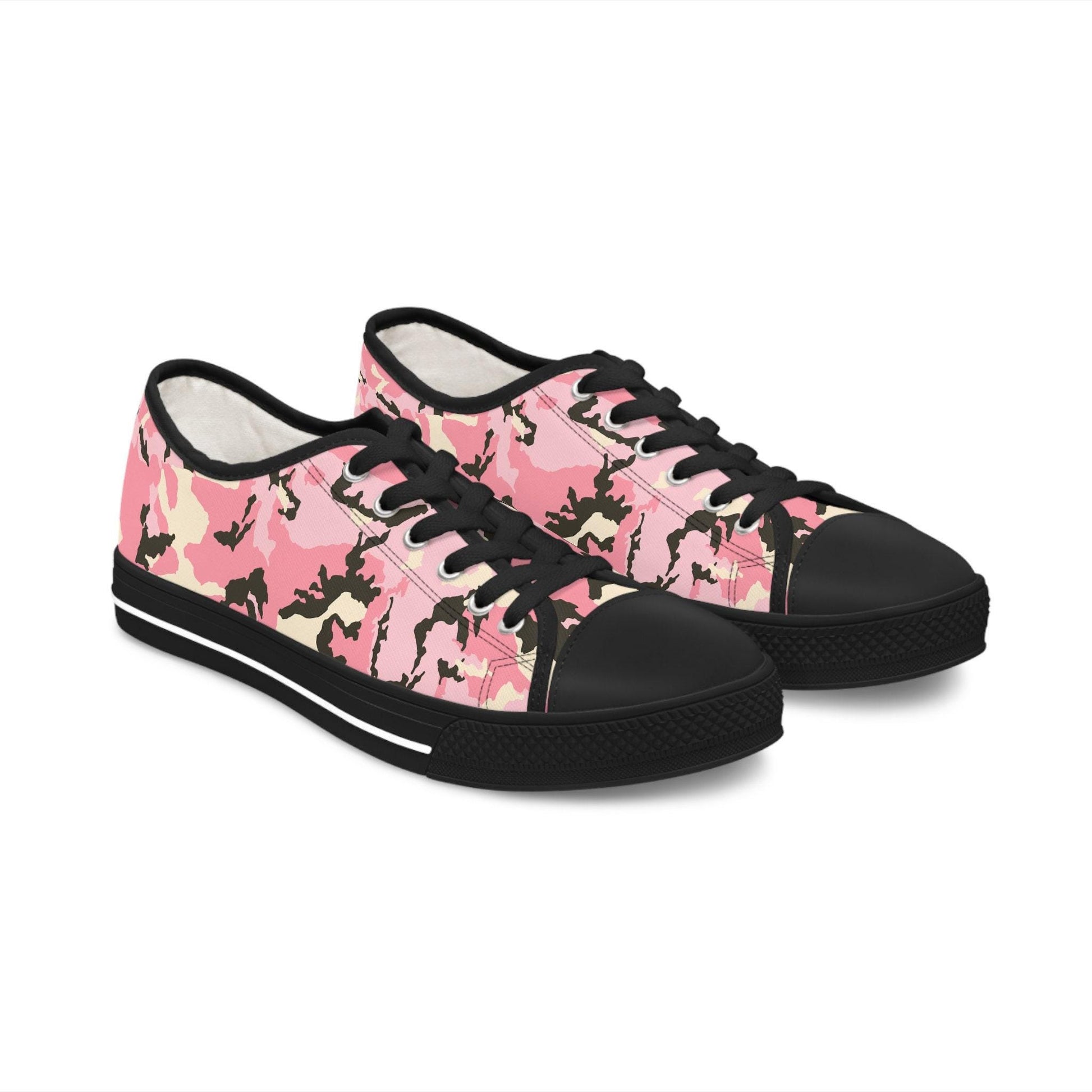 Pair of pink camouflage low-top canvas sneakers with black laces, black rubber toe caps, and black soles featuring a white stripe—bold and stylish shoes for casual streetwear fashion.