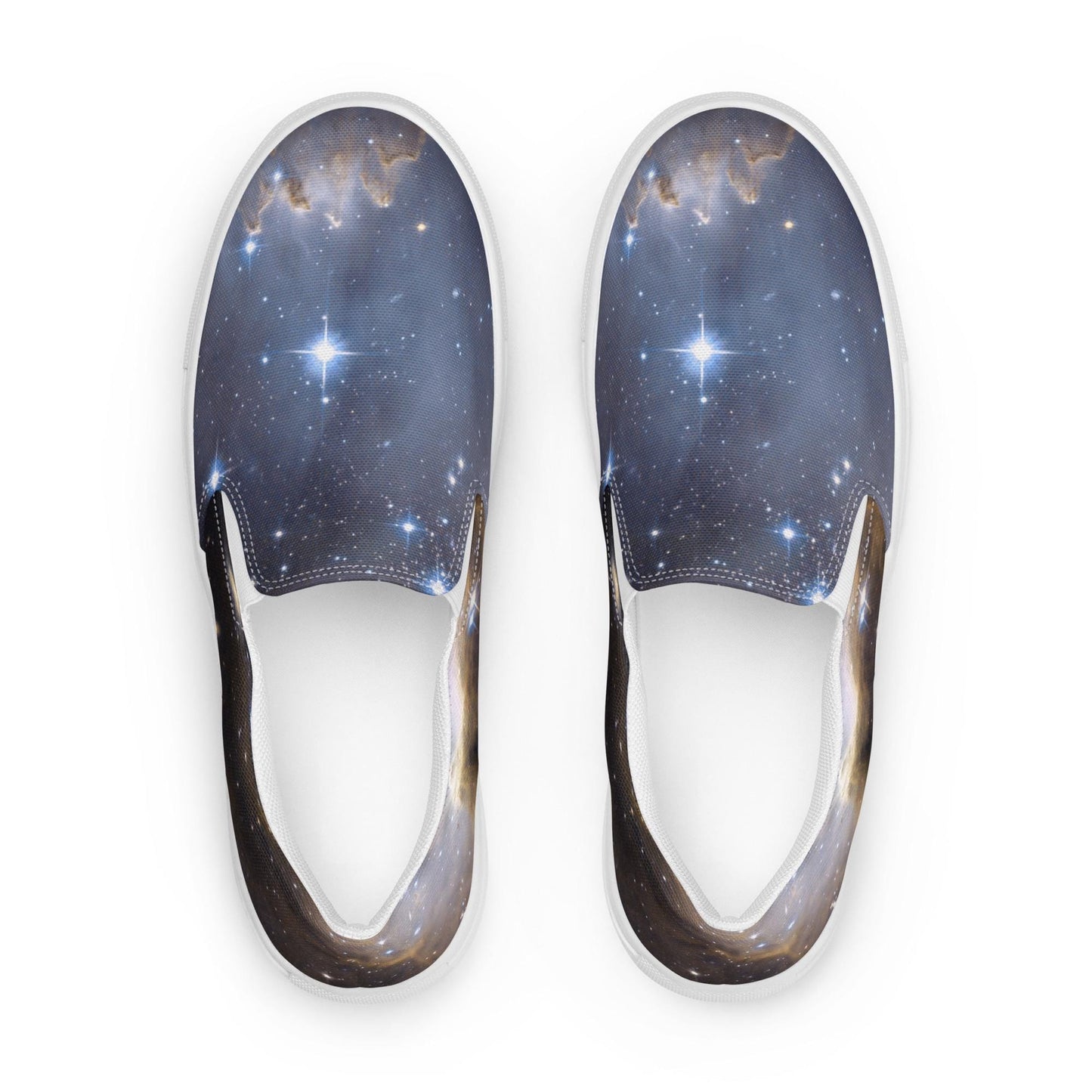 Top-down view of a pair of slip-on sneakers featuring a stunning galaxy print with stars, nebulae, and cosmic clouds in deep blues and subtle gold tones. The shoes have white elastic side panels and white soles, displayed against a clean white background.