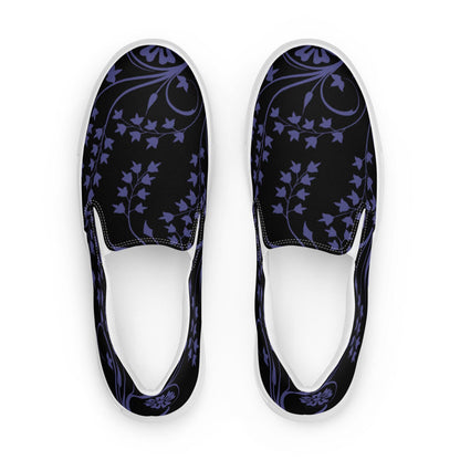Top-down view of slip-on sneakers featuring a black canvas base with a deep purple floral and ivy vine pattern. The design includes curved vine accents and stylized blossoms, complemented by white inner lining and soles for a clean, modern contrast.