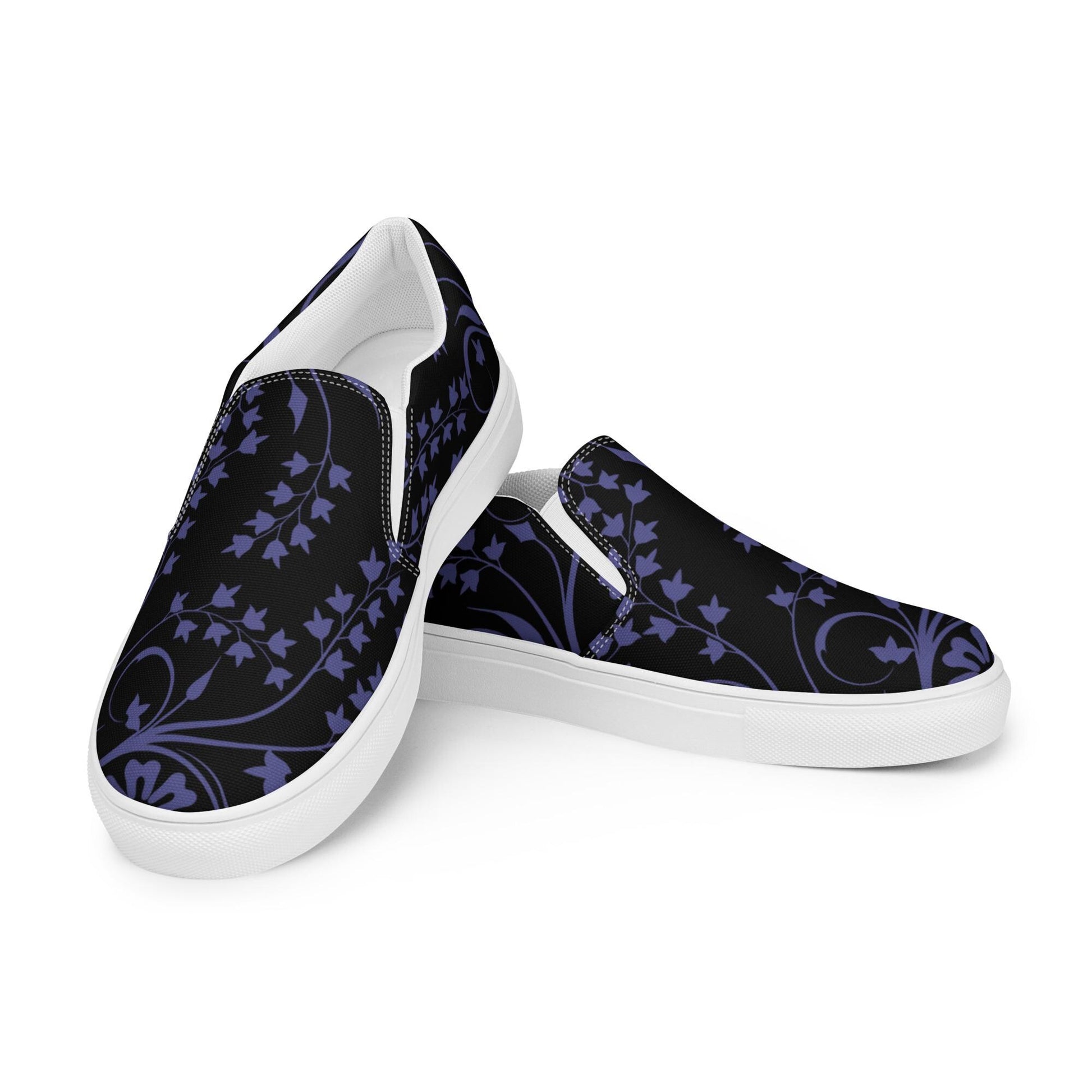 Pair of slip-on sneakers with a black canvas upper featuring an elegant dark purple ivy and floral pattern. The shoes have clean white soles and elastic side panels, designed for easy wear and casual style.