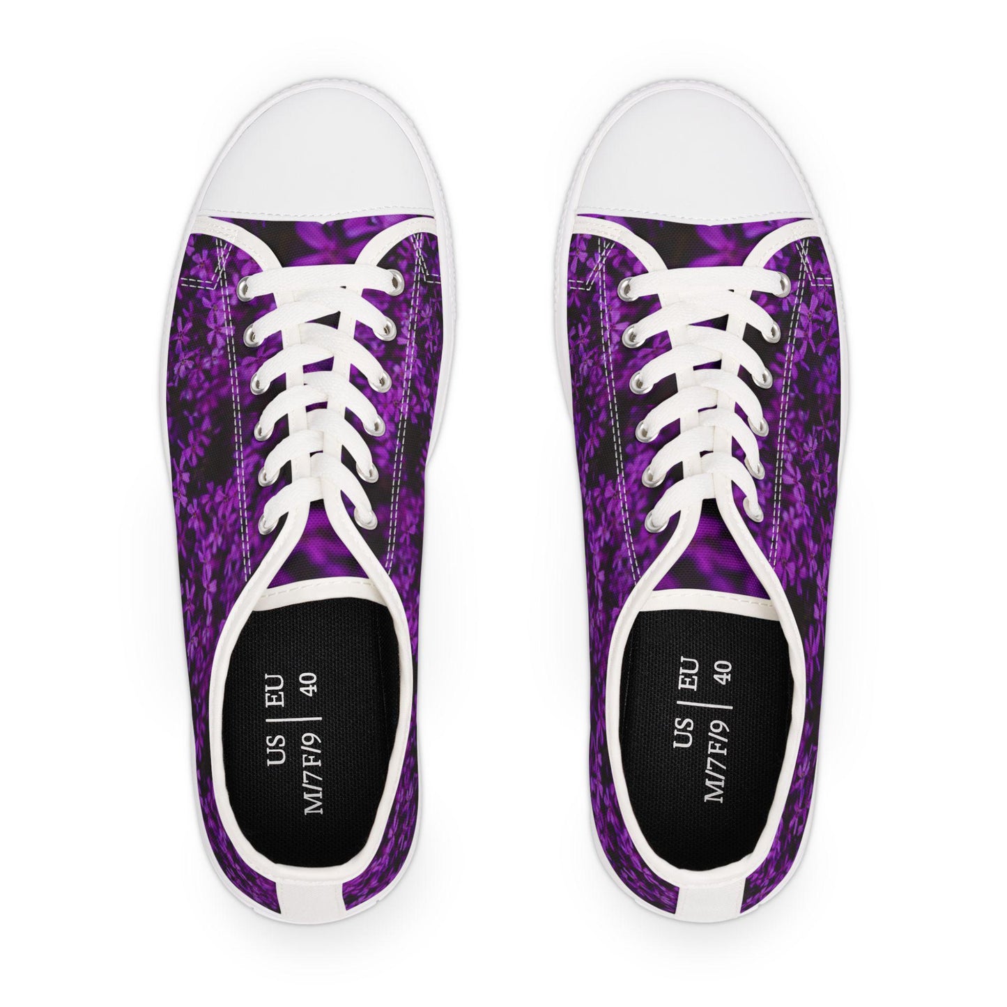 Top view of a pair of low-top sneakers featuring a vibrant purple floral pattern on a dark background. The shoes have white laces, white rubber toe caps, and white trim. The black insoles are printed with size information: US M7/F9 and EU 40. The clean design creates a bold contrast that highlights the colorful pattern.