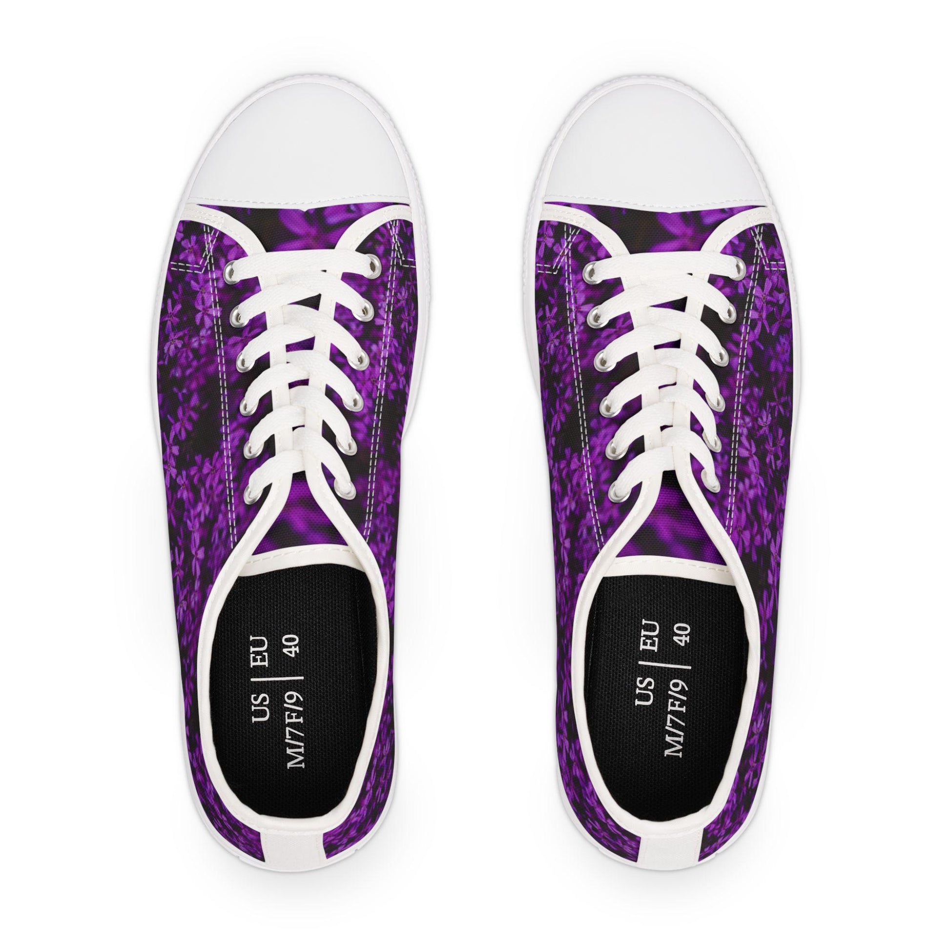 Top view of a pair of low-top sneakers featuring a vibrant purple floral pattern on a dark background. The shoes have white laces, white rubber toe caps, and white trim. The black insoles are printed with size information: US M7/F9 and EU 40. The clean design creates a bold contrast that highlights the colorful pattern.
