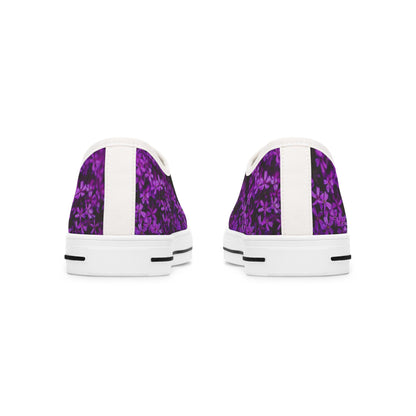 Rear view of a pair of low-top sneakers featuring a vibrant purple floral pattern on a dark background. Each shoe has a vertical white strip running down the back, complementing the white soles with black accent lines. The design creates a clean and modern contrast with the bold, colorful upper.