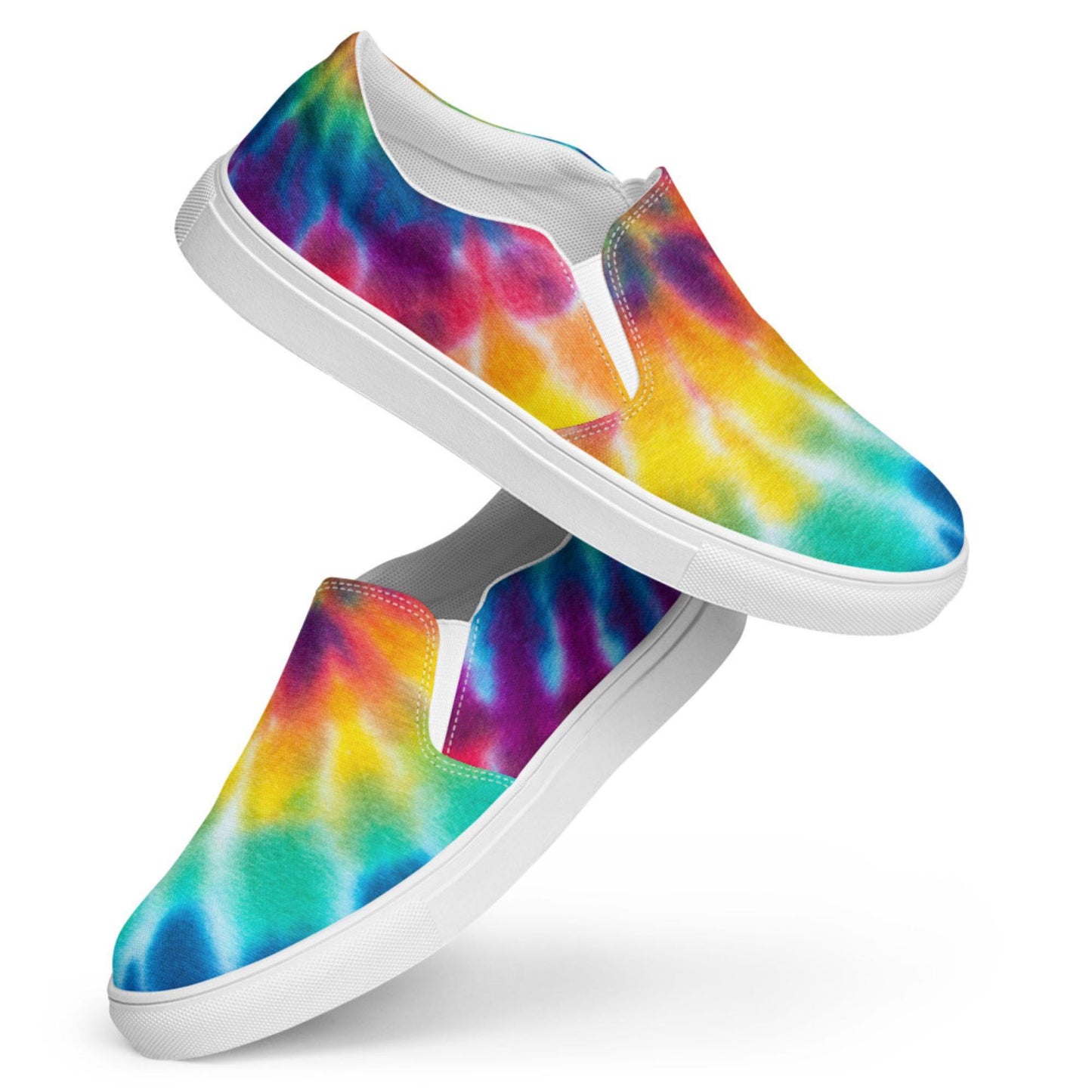 Floating display of colorful rainbow tie-dye slip-on canvas sneakers against a white background. These bold women’s casual shoes feature a vibrant watercolor pattern with turquoise, blue, yellow, orange, red, and purple hues. Designed with a sleek white rubber sole and elastic side panels for comfort and easy on/off wear.