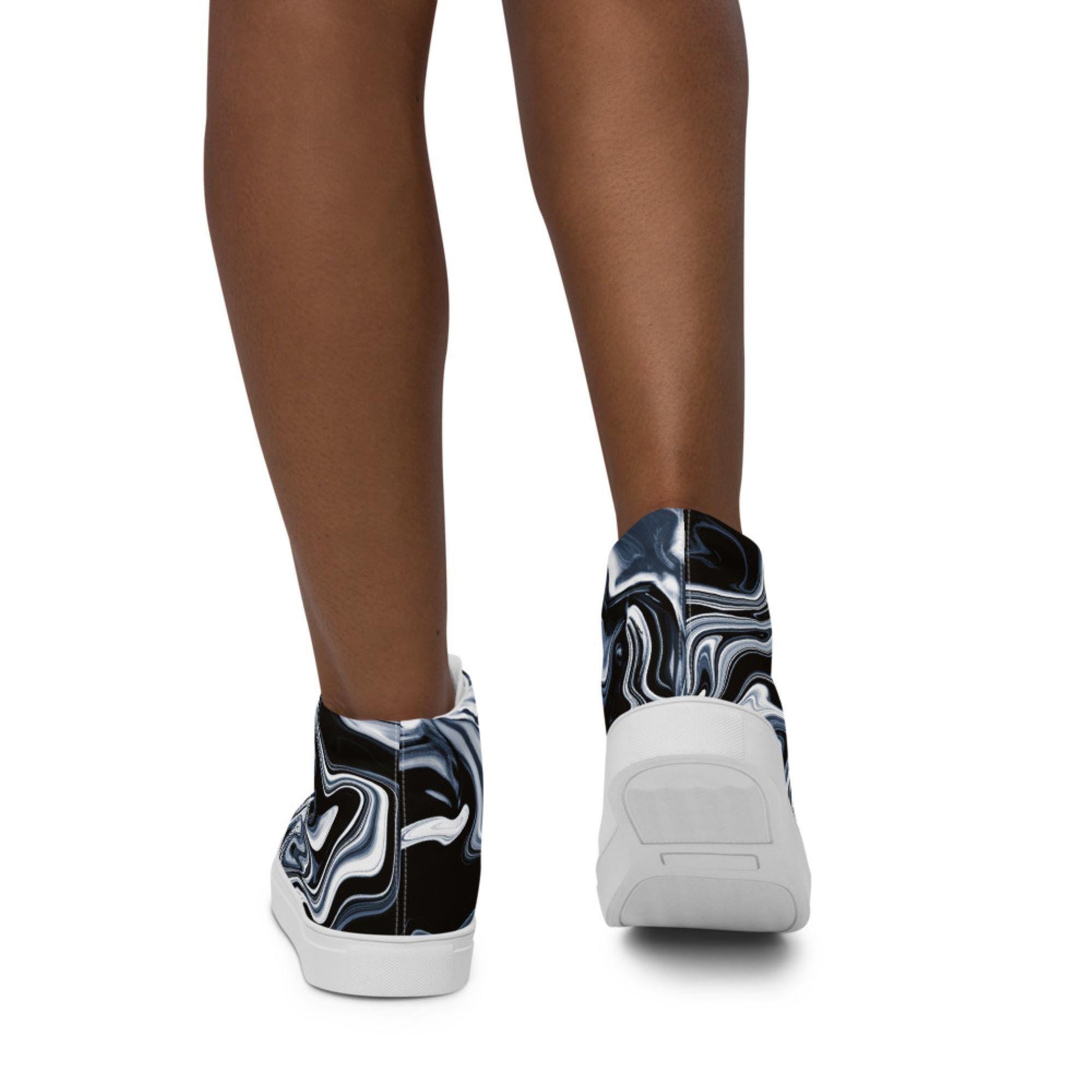 Rear view of a person wearing high-top sneakers with a bold black, white, and blue marbled swirl design. The shoes feature white soles and are showcased against a plain white background, highlighting the dynamic pattern on the back of the sneakers.