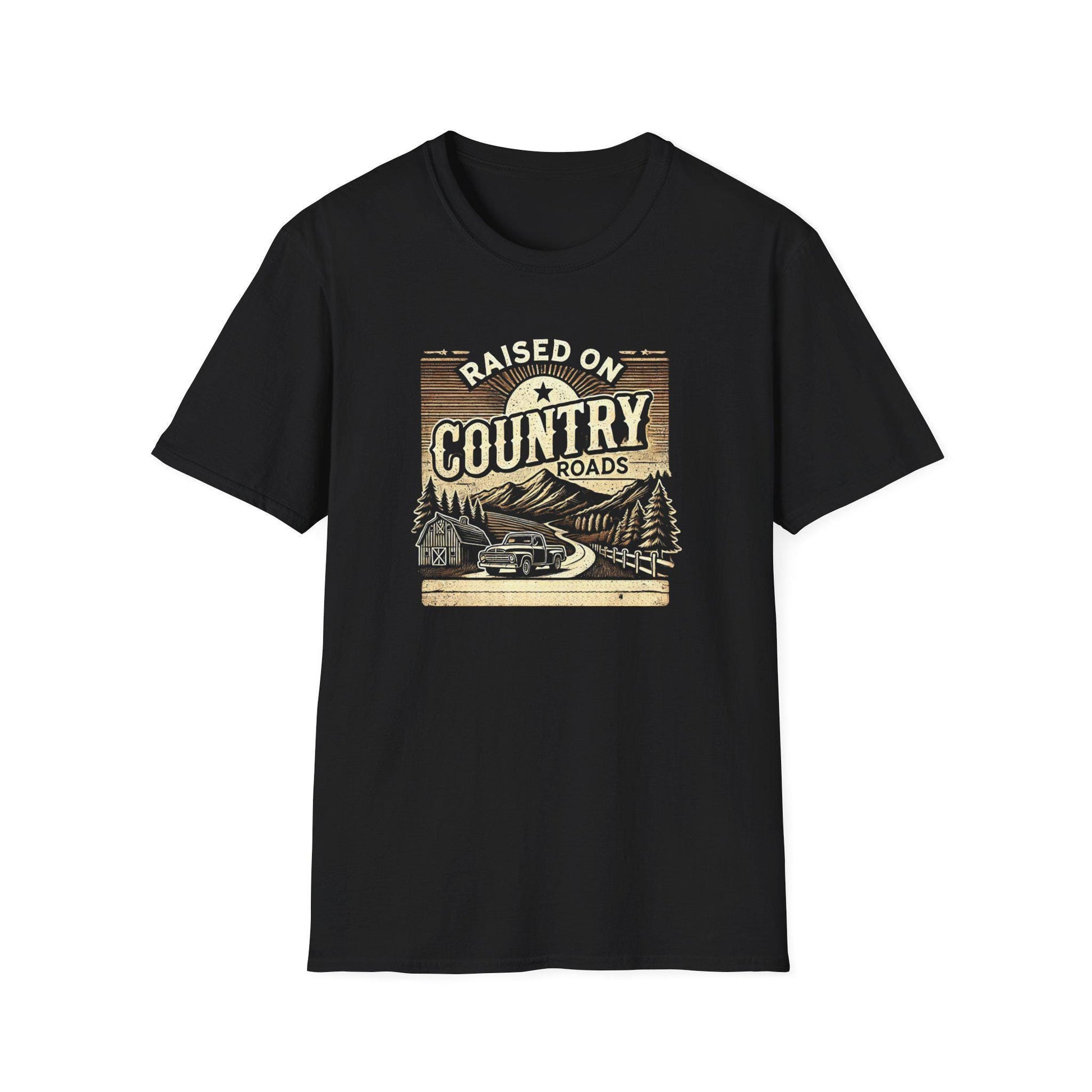 A black unisex t-shirt laid flat against a white background, featuring a vintage-inspired graphic that reads &quot;Raised on Country Roads.&quot; The design includes an old pickup truck driving along a winding road through a rural scene with pine trees, a barn, mountains, and a rising sun. The artwork has a rustic, retro feel with muted tan and brown tones.