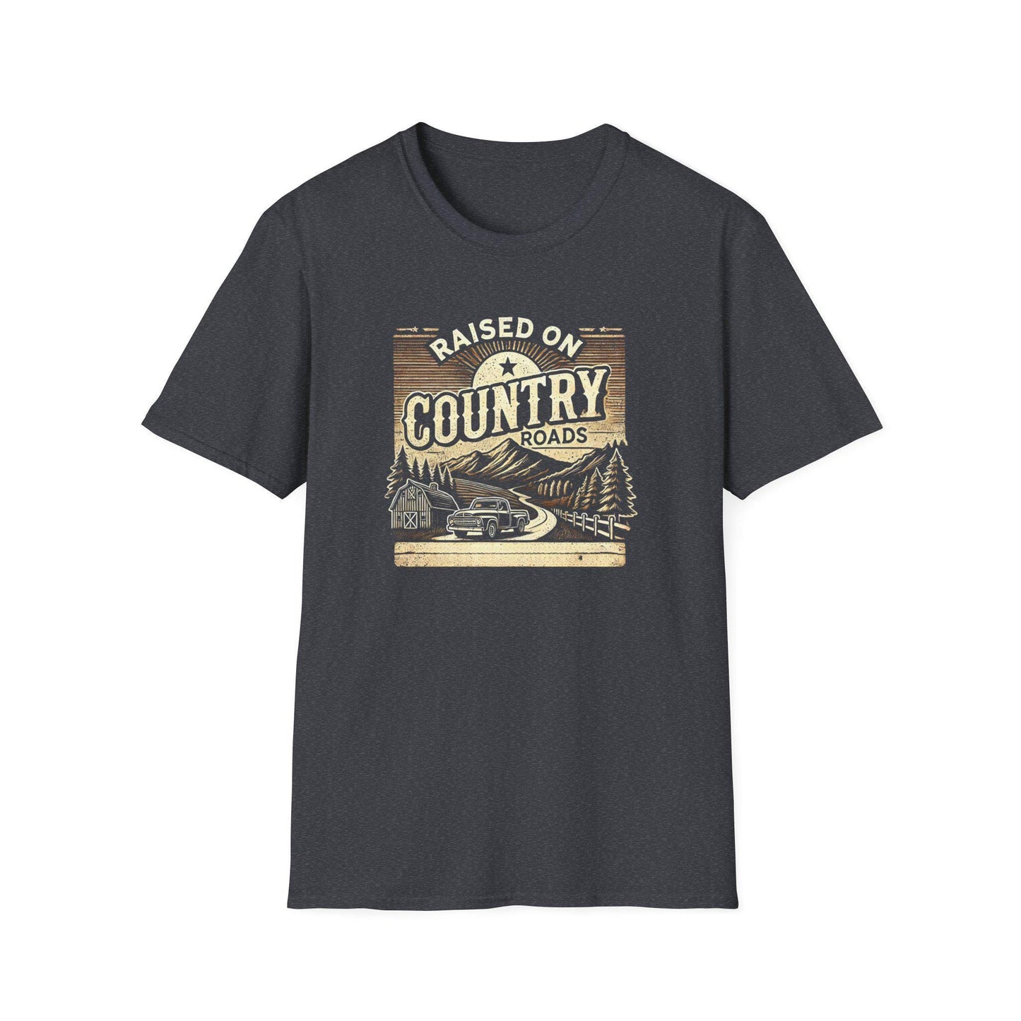 A dark heather gray unisex t-shirt is displayed flat on a white background, featuring a vintage-style graphic with the text &quot;Raised on Country Roads.&quot; The artwork shows a classic truck driving along a winding road through a rural landscape with pine trees, a barn, and distant mountains under a rising sun. The design uses muted tan, cream, and brown tones to create a nostalgic, rustic country feel.
