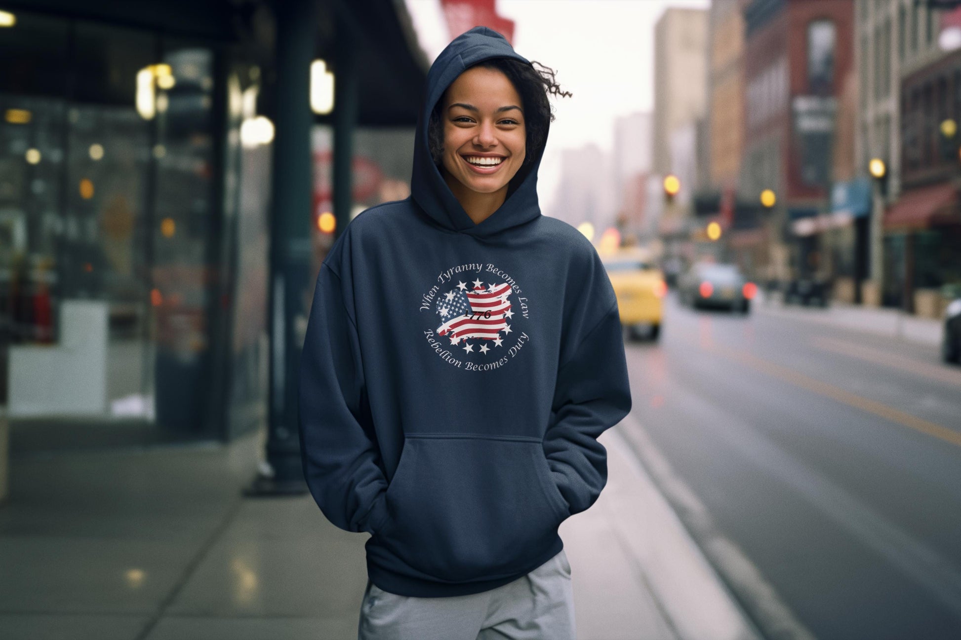 Patriotic graphic hoodie featuring a distressed American flag and the quote “When Tyranny Becomes Law, Rebellion Becomes Duty” worn by a smiling young woman standing on a city sidewalk. USA freedom slogan pullover sweatshirt for women, casual streetwear style. Perfect for conservative fashion, political statement apparel, or patriotic gift ideas.