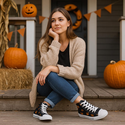 Young woman sitting on a wooden porch decorated for Halloween with pumpkins, hay bales, and orange bunting. She is wearing a beige cardigan, jeans, and black high-top sneakers featuring orange jack-o&#39;-lantern faces. A Halloween wreath hangs on the door behind her, creating a festive autumn atmosphere.