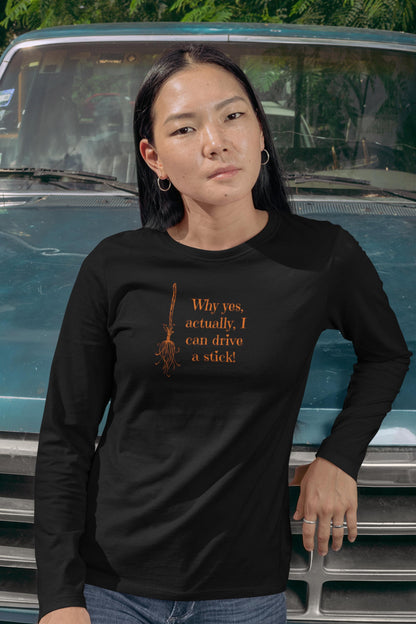 Woman wearing a black long-sleeve Halloween shirt with orange broomstick graphic and funny witch quote &quot;Why yes, actually, I can drive a stick!&quot; — perfect for spooky season, fall vibes, and Halloween parties. Ideal witch-themed shirt for women, Halloween apparel with attitude, and autumn novelty tee for October celebrations.