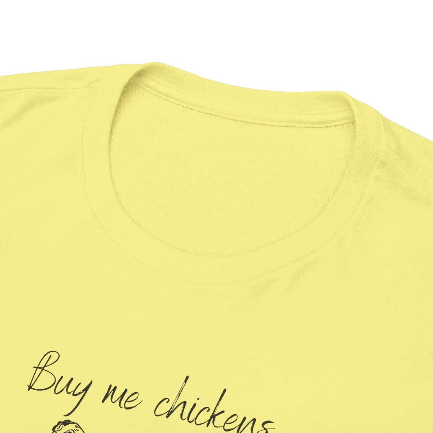Close-up image of the neckline and upper chest area of a light yellow T-shirt. The shirt features a cleanly stitched crew neck and part of a printed design with the text &quot;Buy me chickens&quot; visible in black script. The fabric appears soft and smooth, showcasing quality construction.