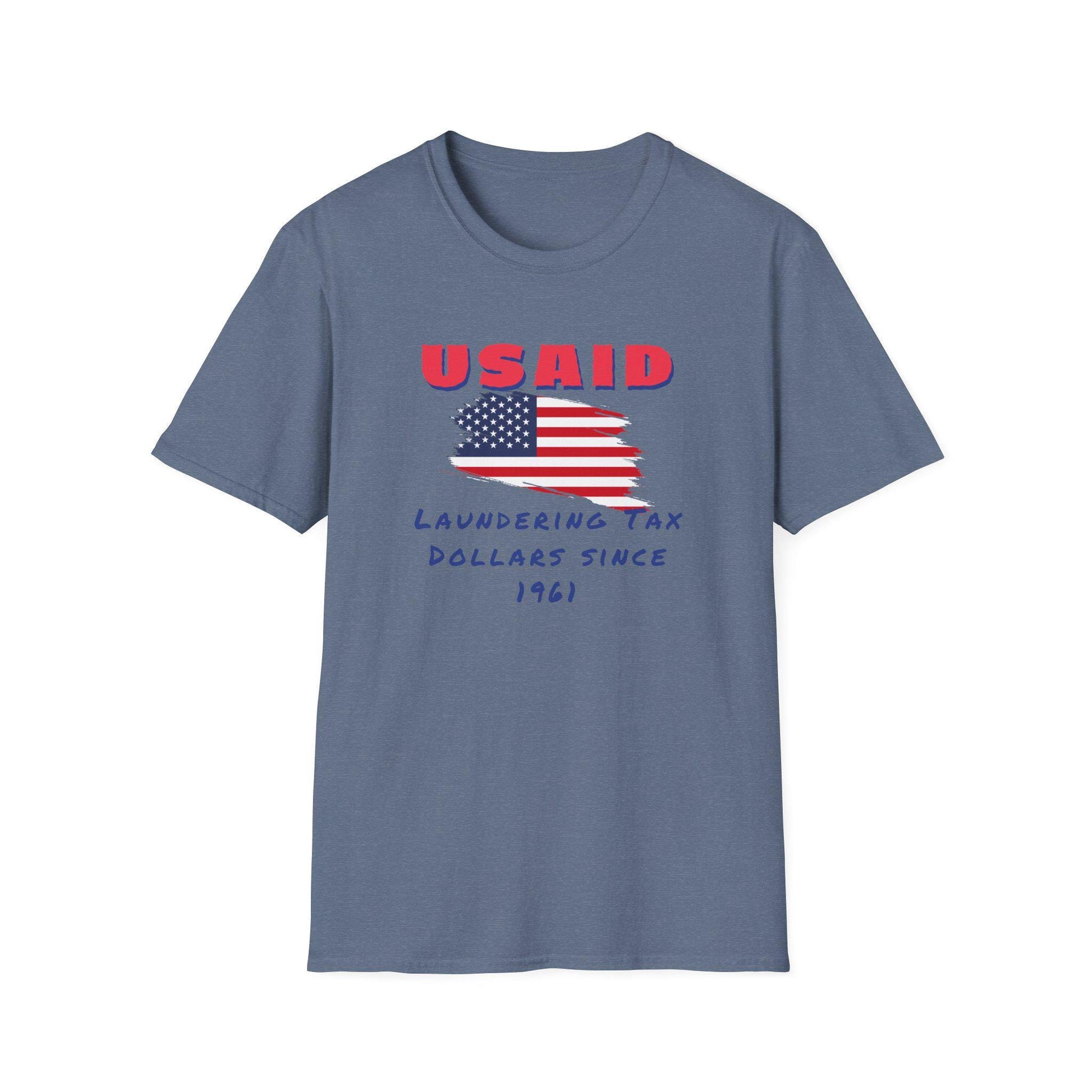 A denim blue T-shirt is displayed flat against a white background. The shirt features a distressed graphic of the American flag in the center. Above the flag, bold red text reads &quot;USAID&quot; in all caps. Below the flag, handwritten-style blue text says: &quot;Laundering Tax Dollars Since 1961.&quot; The design conveys a satirical political message with a rugged, protest-themed aesthetic.