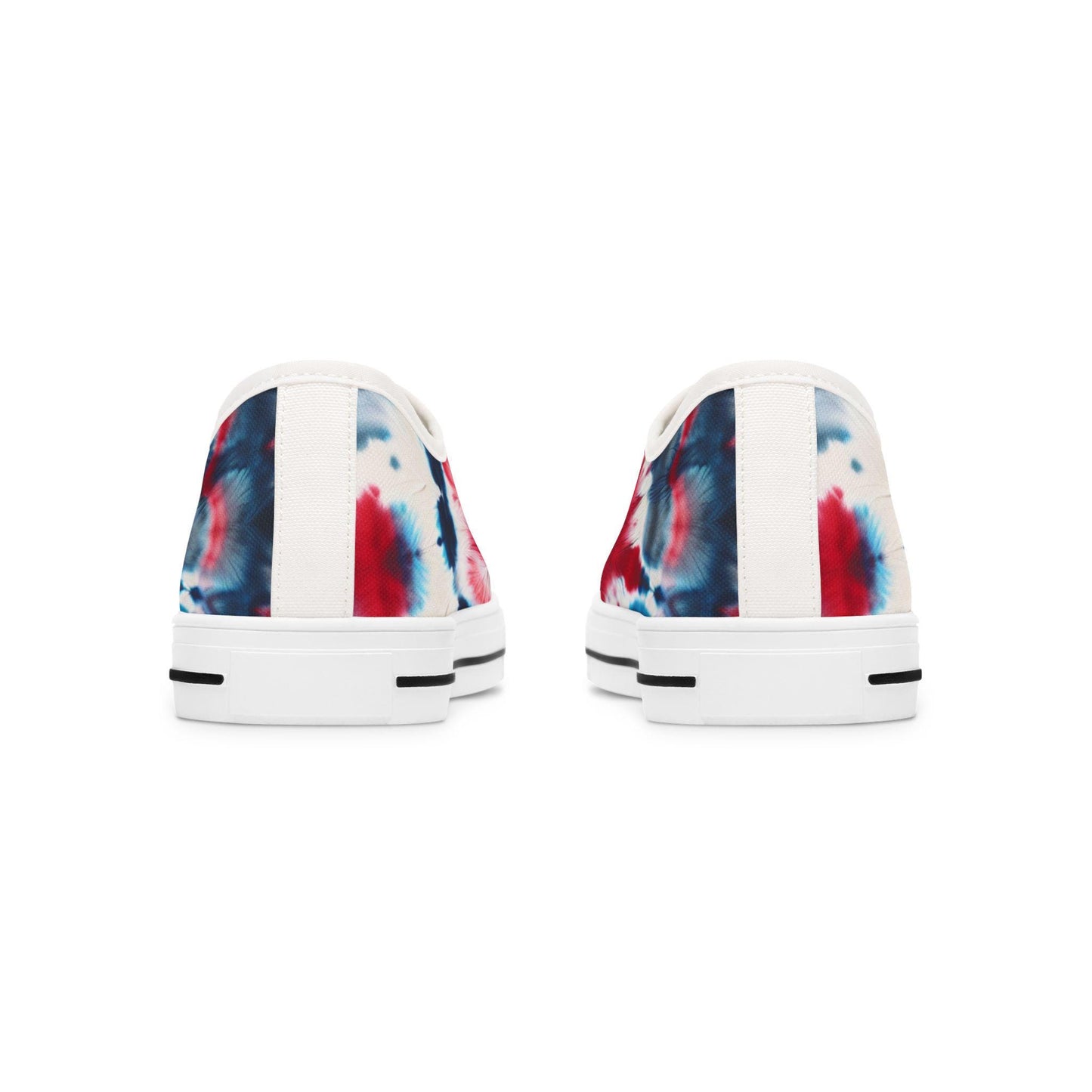 Rear view of a pair of low-top canvas sneakers showcasing a bold red, white, and blue tie-dye design. The shoes feature white heels with a vertical fabric strip down the center and white rubber soles accented with black horizontal lines near the bottom. The vibrant patriotic pattern wraps around the back, adding a festive touch perfect for casual summer wear.