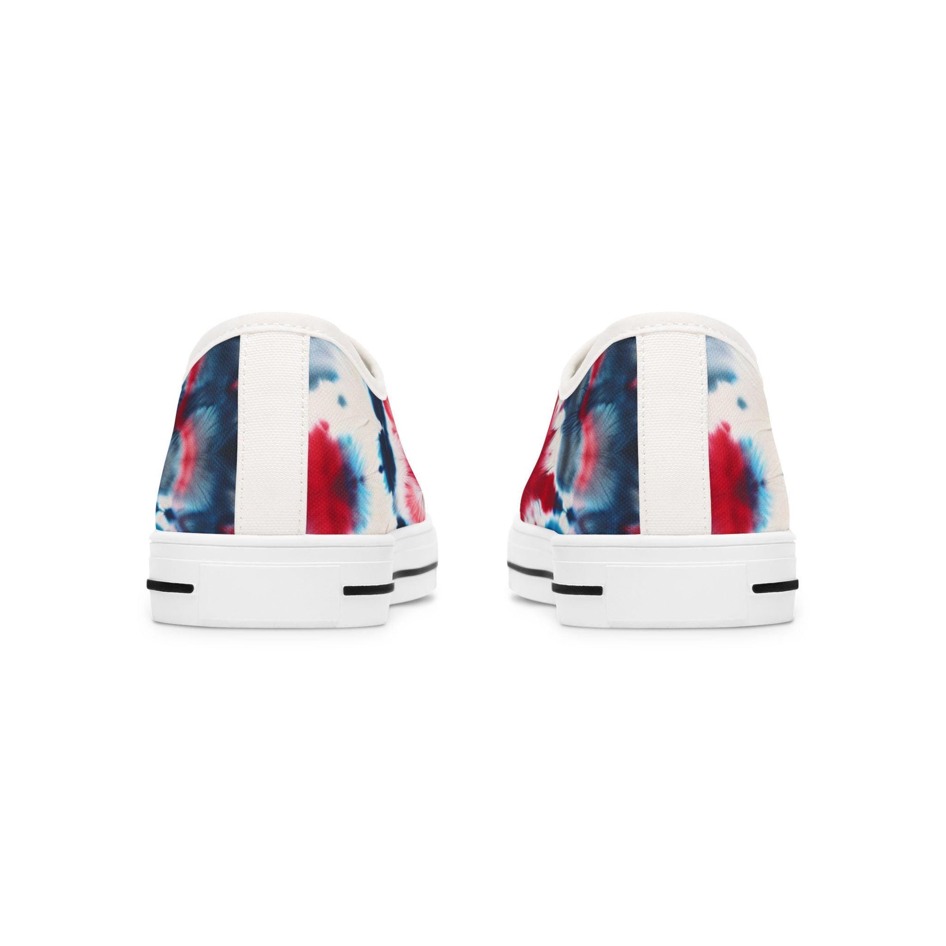 Rear view of a pair of low-top canvas sneakers showcasing a bold red, white, and blue tie-dye design. The shoes feature white heels with a vertical fabric strip down the center and white rubber soles accented with black horizontal lines near the bottom. The vibrant patriotic pattern wraps around the back, adding a festive touch perfect for casual summer wear.