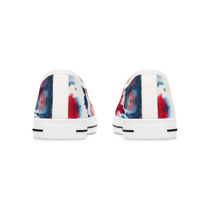 Rear view of a pair of low-top canvas sneakers showcasing a bold red, white, and blue tie-dye design. The shoes feature white heels with a vertical fabric strip down the center and white rubber soles accented with black horizontal lines near the bottom. The vibrant patriotic pattern wraps around the back, adding a festive touch perfect for casual summer wear.