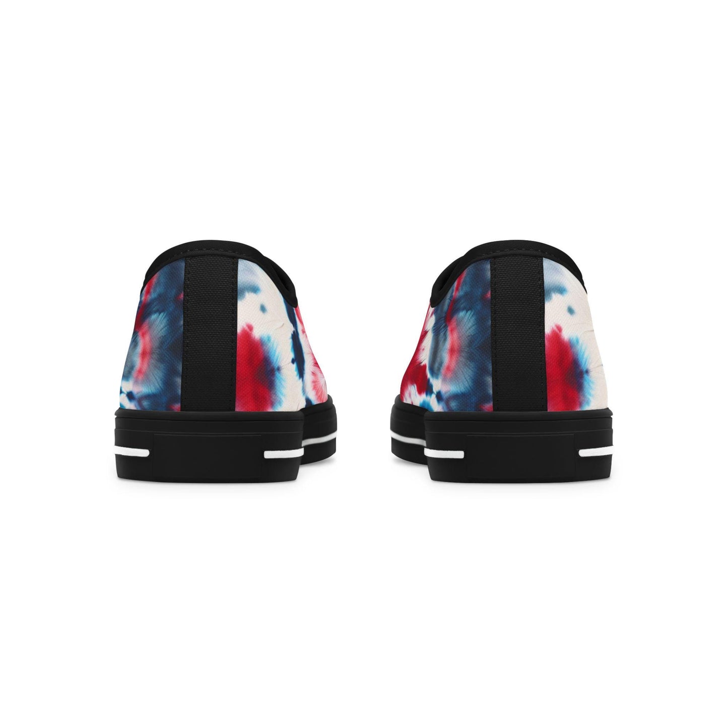 Rear view of a pair of low-top canvas sneakers featuring a vibrant red, white, and blue tie-dye design. These shoes have black heels with a vertical fabric strip and black rubber soles accented by white horizontal lines. The bold patriotic color scheme wraps around the back, giving the sneakers a festive and stylish look perfect for summer celebrations or everyday wear.