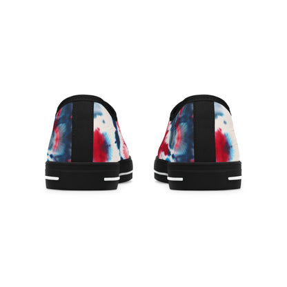 Rear view of a pair of low-top canvas sneakers featuring a vibrant red, white, and blue tie-dye design. These shoes have black heels with a vertical fabric strip and black rubber soles accented by white horizontal lines. The bold patriotic color scheme wraps around the back, giving the sneakers a festive and stylish look perfect for summer celebrations or everyday wear.