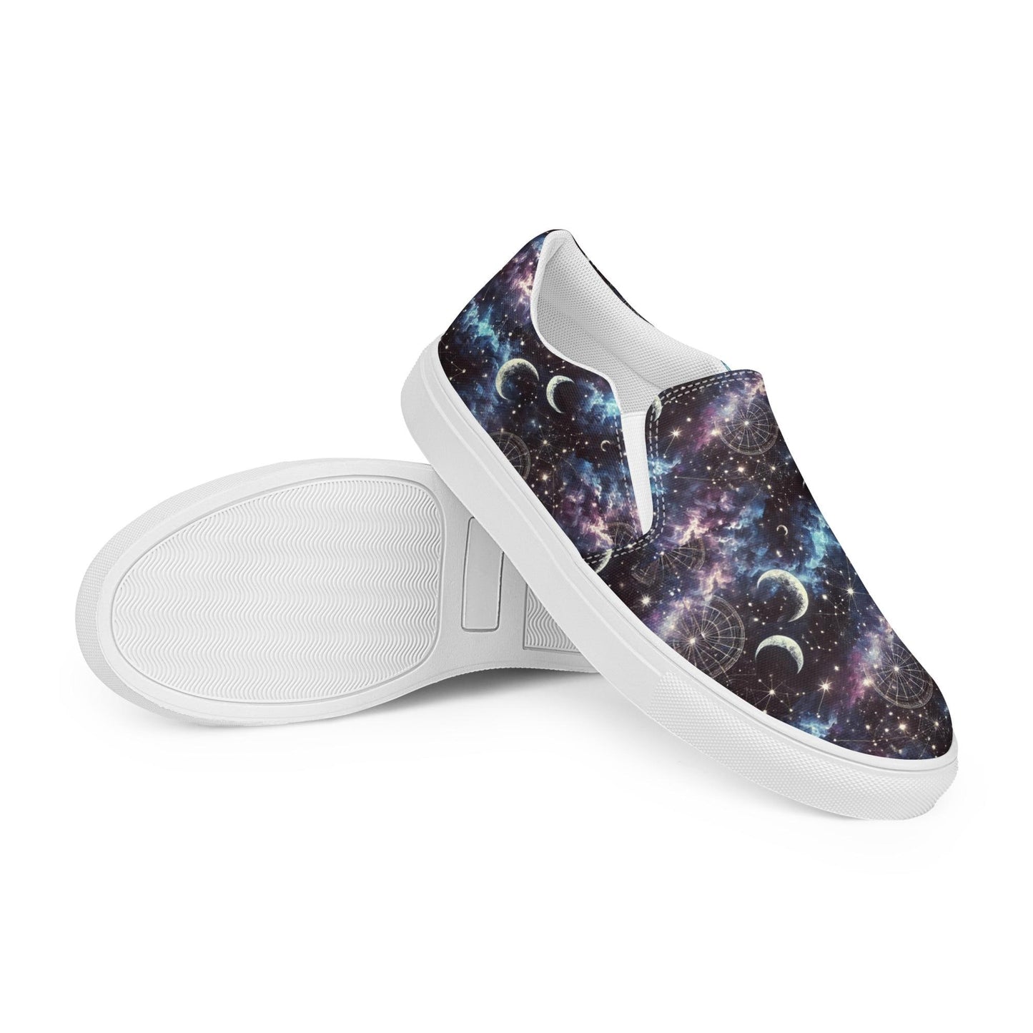 Pair of slip-on canvas shoes with white soles featuring a vibrant galaxy-themed design. The pattern includes stars, nebulae, crescent moons, and celestial charts in shades of purple, blue, and black. One shoe is laid flat to display the sole&#39;s texture, while the other is positioned upright to showcase the outer design.