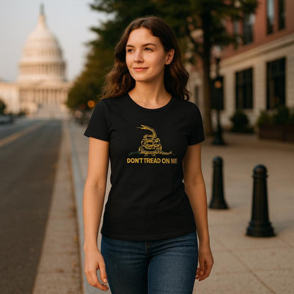 Woman walking confidently down a city street wearing a fitted black t-shirt featuring a yellow coiled rattlesnake and the text &quot;DON&#39;T TREAD ON ME.&quot; The U.S. Capitol building is visible in the background, suggesting a patriotic or political theme.